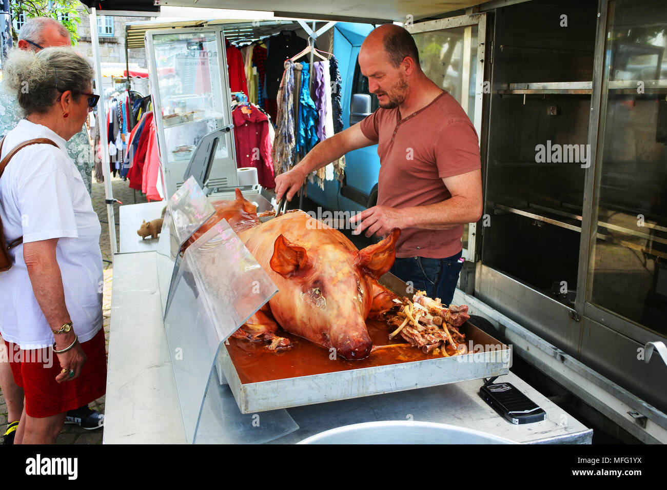 Whole roasted pig being carved at a French market, Huelgoat, Brittany - John Gollop Stock Photo