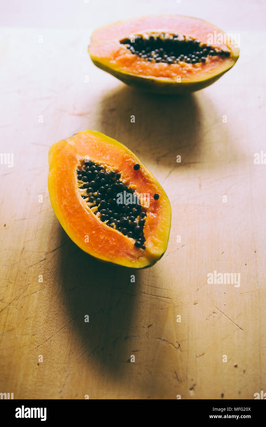 Close up of tropical fruit papaya cut i half on a wooden background Stock Photo