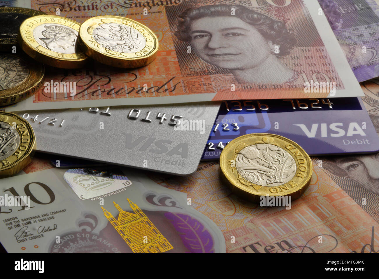 British ten Pound notes and one Pound coins with Visa debit and credit cards close-up Stock Photo