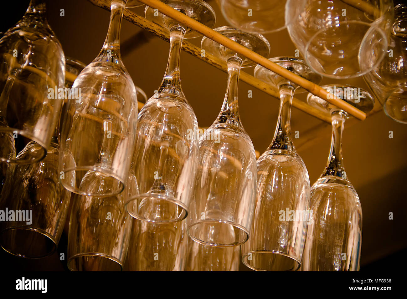 Glasses hanging upsidedown in wine bar interior Stock Photo