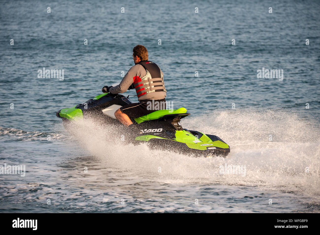 Middle aged man wearing a life vest rides a personal water craft Jet