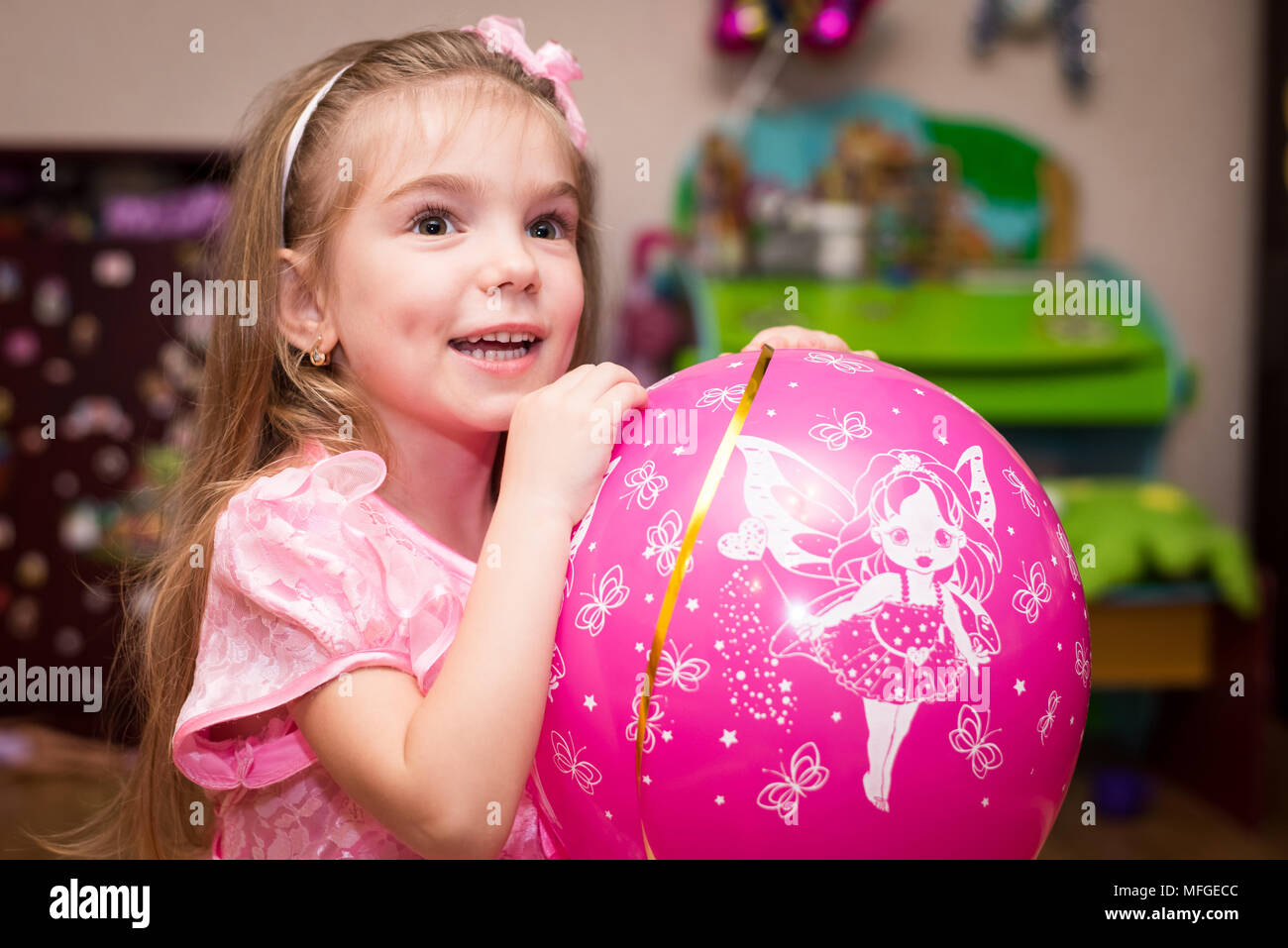 Little girl in a beautiful pink dress with a ball in the children's ...
