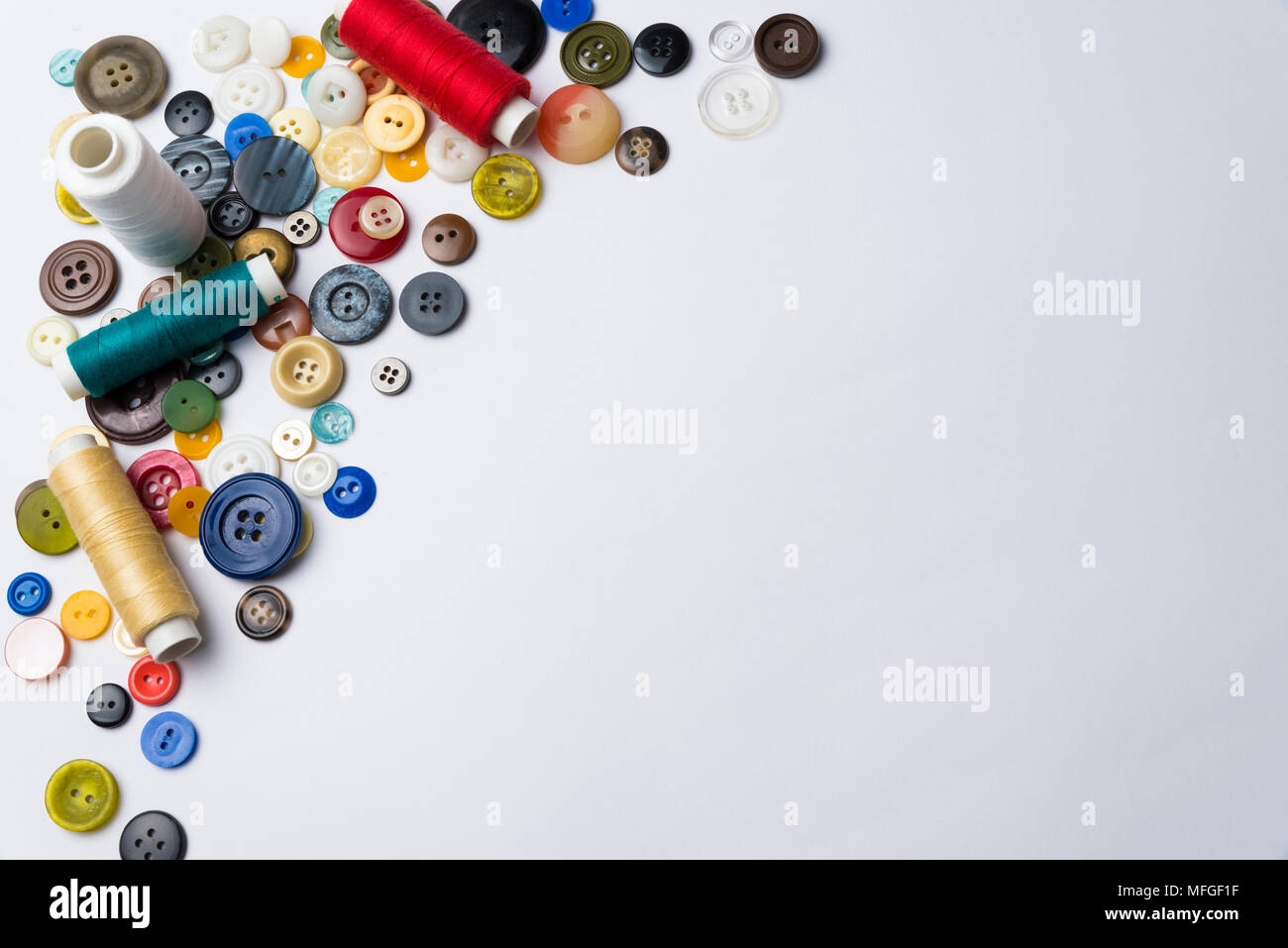 multi-colored buttons and coils with threads lie on a white surface Stock Photo