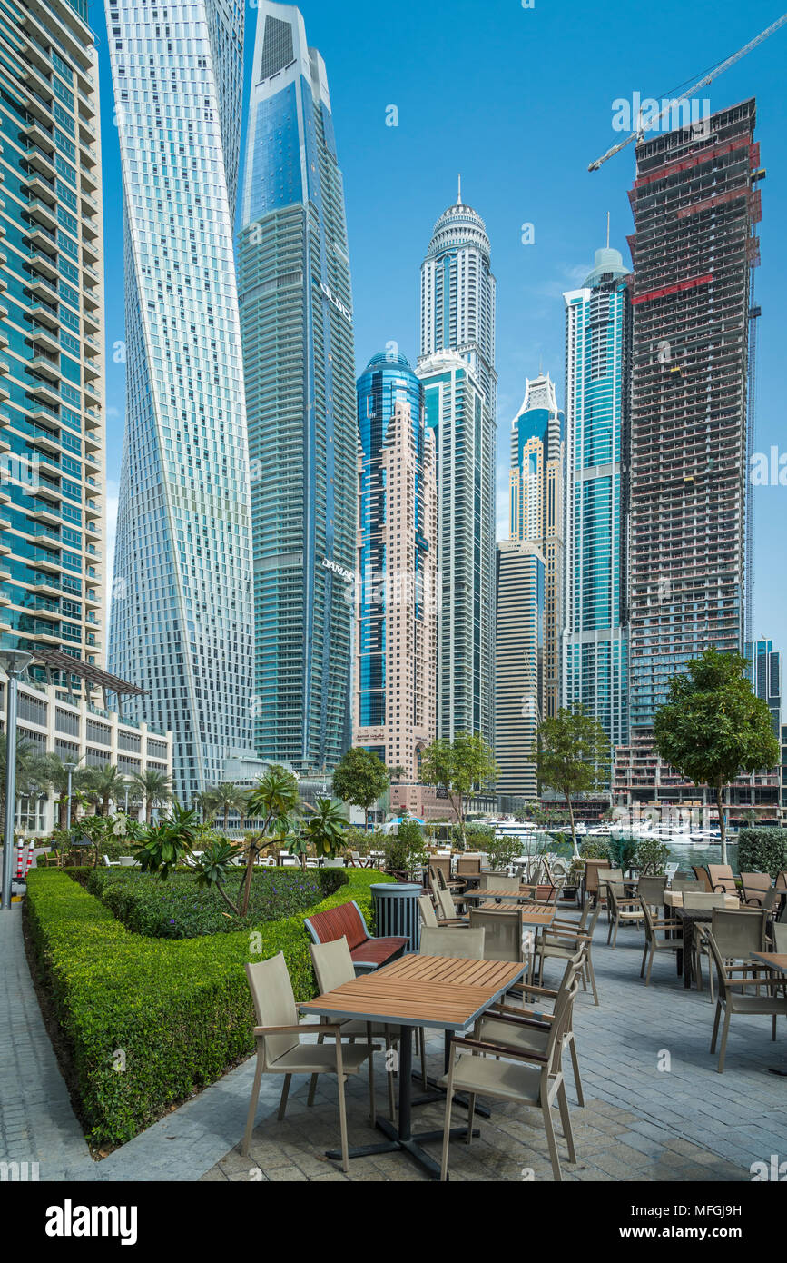 An outdoor restaurant and tall buildings of the Dubai marina, UAE