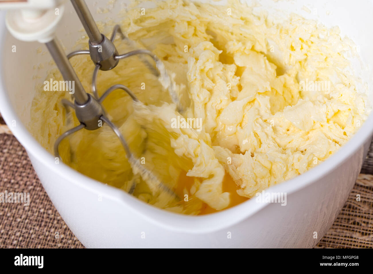 Mixing butter and eggs in white bowl with motor mixer. Photo can be used as a whole background