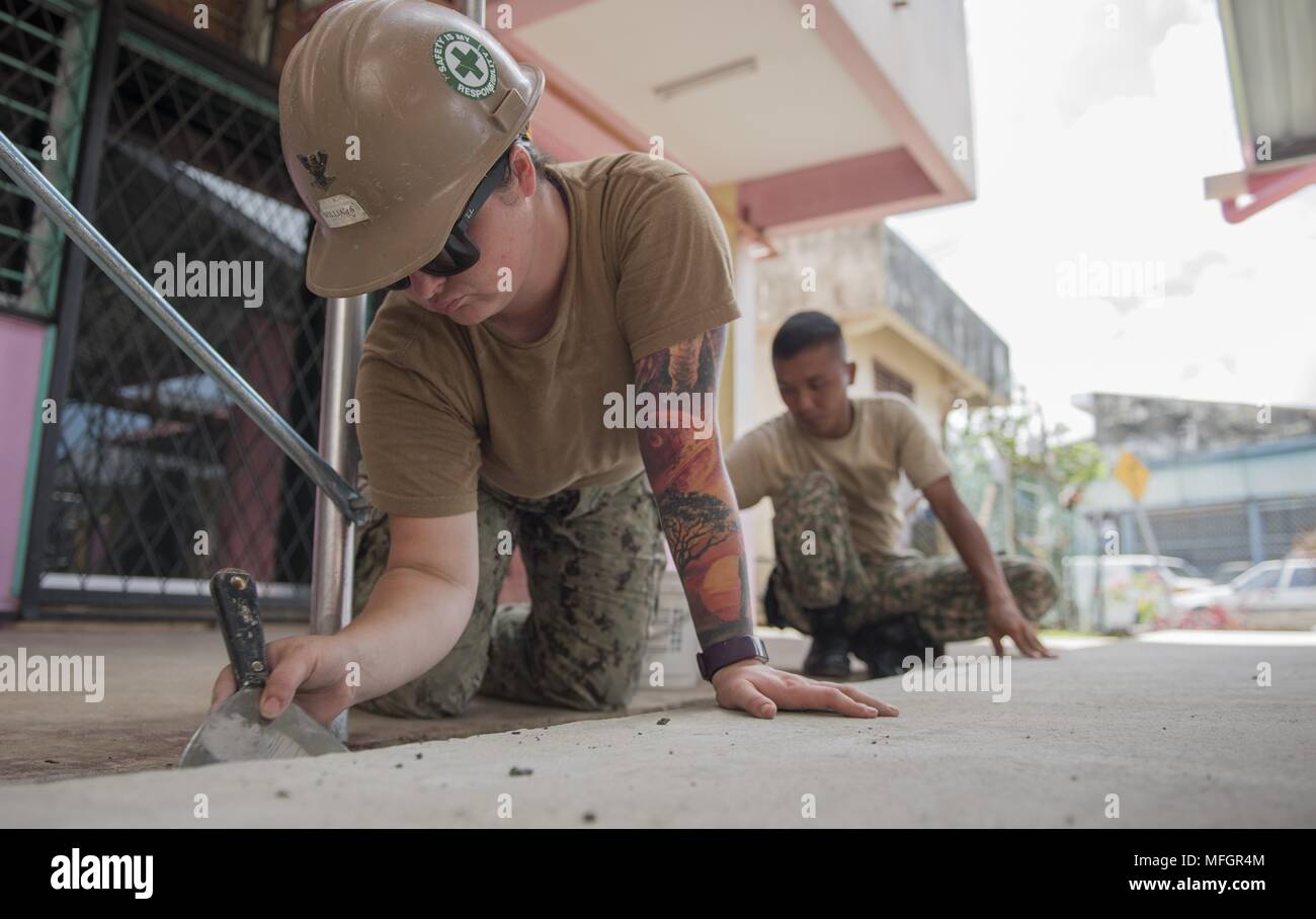 180424-N-OU129-091 TAWAU, Malaysia (April 24, 2018) Builder 3rd Class Autumn Williams of Naval Mobile Construction Battalion (NMCB) 5 and a Malaysian Armed Forces member apply grout to a concrete floor at an engineering project at SK Kebangsaan Taman in Tawau, Malaysia as a part of Pacific Partnership 2018 (PP18), April 24, 2018. PP18's mission is to work collectively with host and partner nations to enhance regional interoperability and disaster response capabilities, increased stability and security in the region, and foster new and enduring friendships across the Indo-Pacific Region. Pacifi Stock Photo
