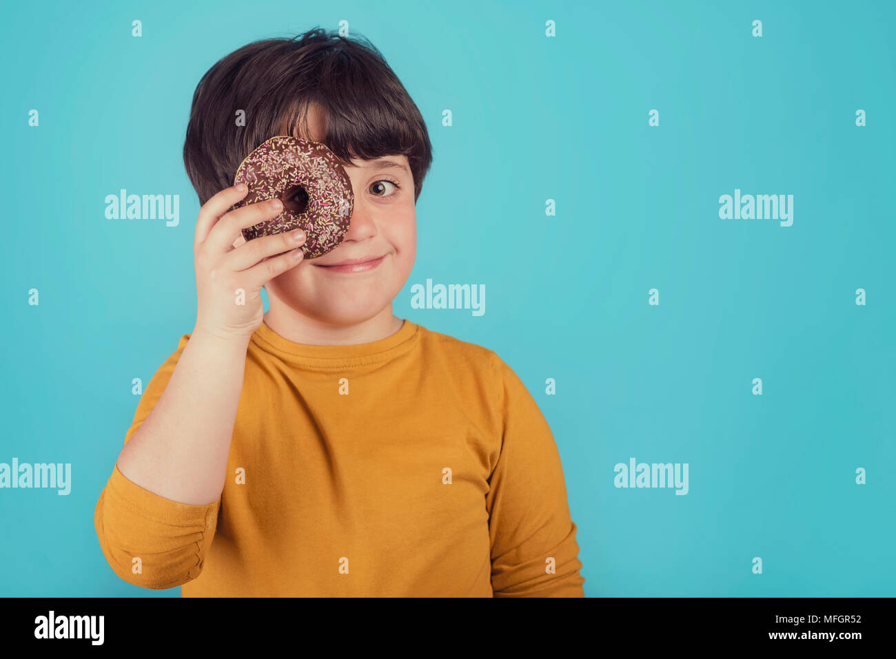 smiling boy holding donuts over her eye smiling boy holding donuts over her eye Stock Photo