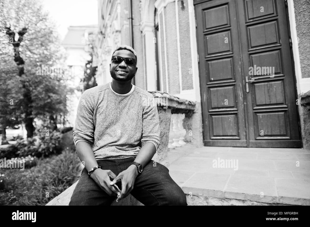 Stylish african american boy on gray sweater and black sunglasses posed on street. Fashionable black guy. Stock Photo
