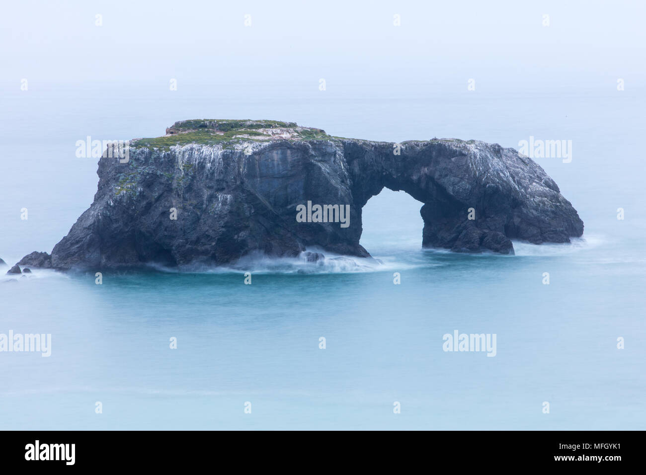 The cold waters of the Pacific Ocean wash against a remote sea stack ...