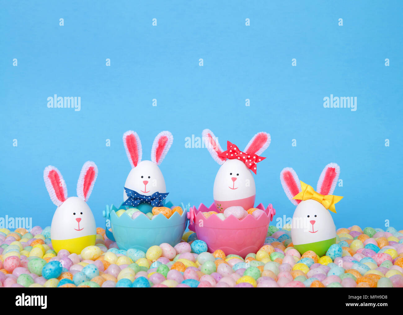 Craft Easter Bunnies made from plastic eggs Two in baskets full of candy with two standing in pastel jelly beans with a light blue background. Fun Eas Stock Photo