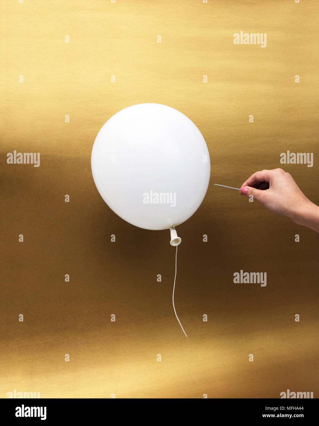 Hand with pin popping a white balloon. Stock Photo