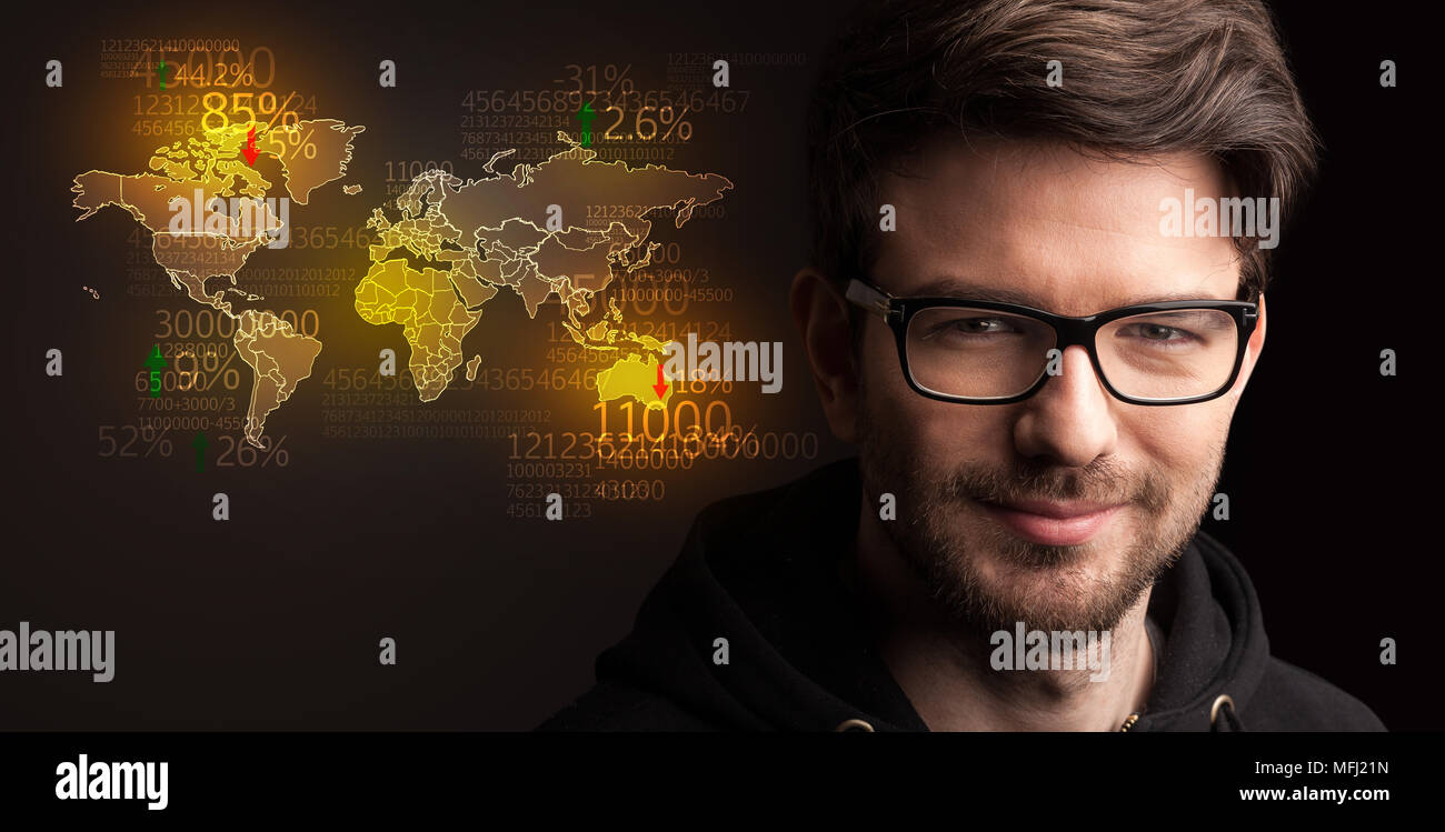 Portrait of a young businessman with a world map and numbers next to him on a dark background Stock Photo