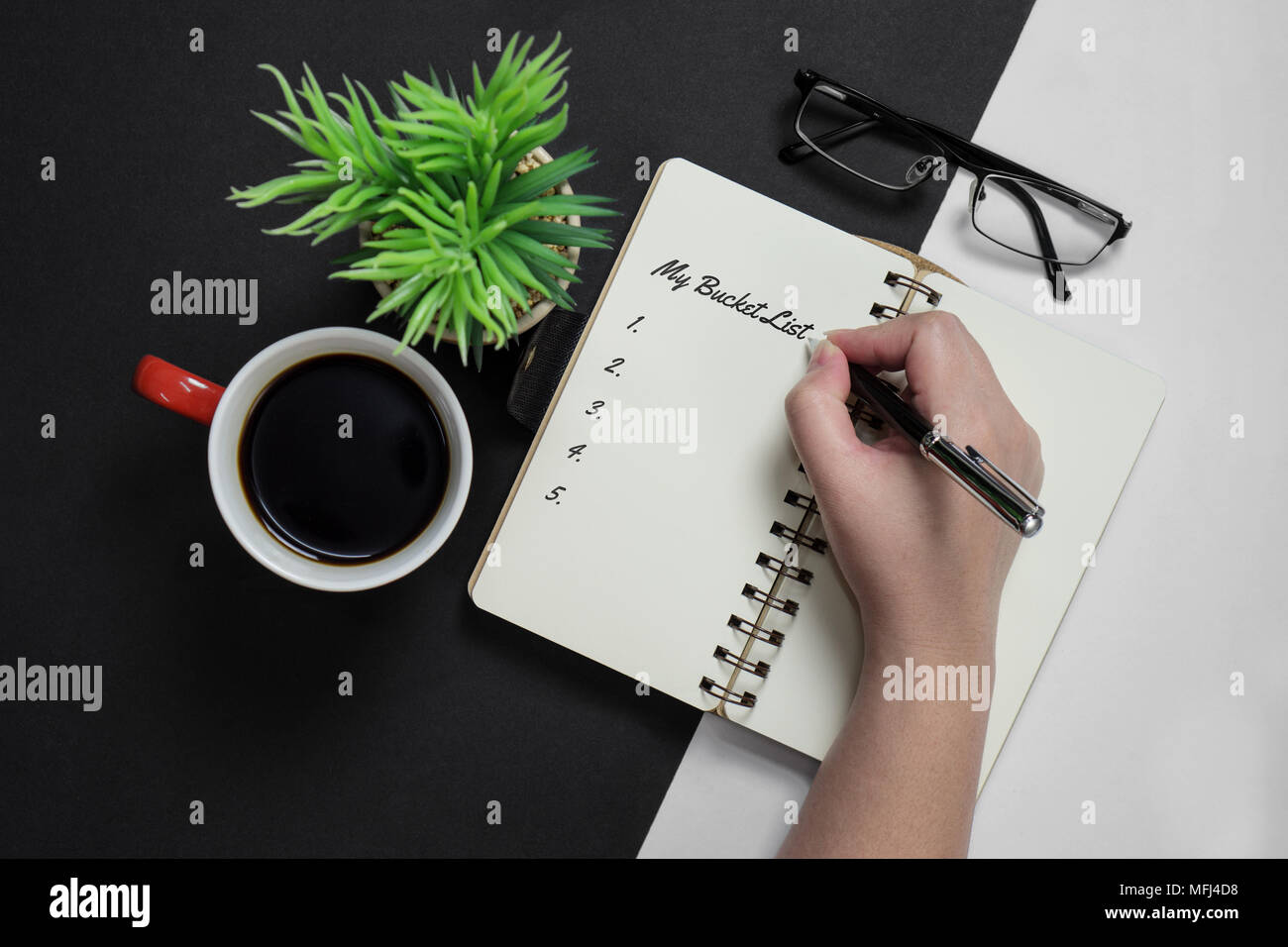 My bucket list. Hand writing on notebook with coffee mug, potted plant and spectacle. Stock Photo