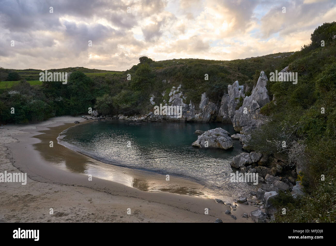 Sunset at Gulpiyuri beach, which is an inland beach arose in flooded sinkhole created by karst erosion (Cantabrian sea, Naves, Llanes, Asturias,Spain) Stock Photo