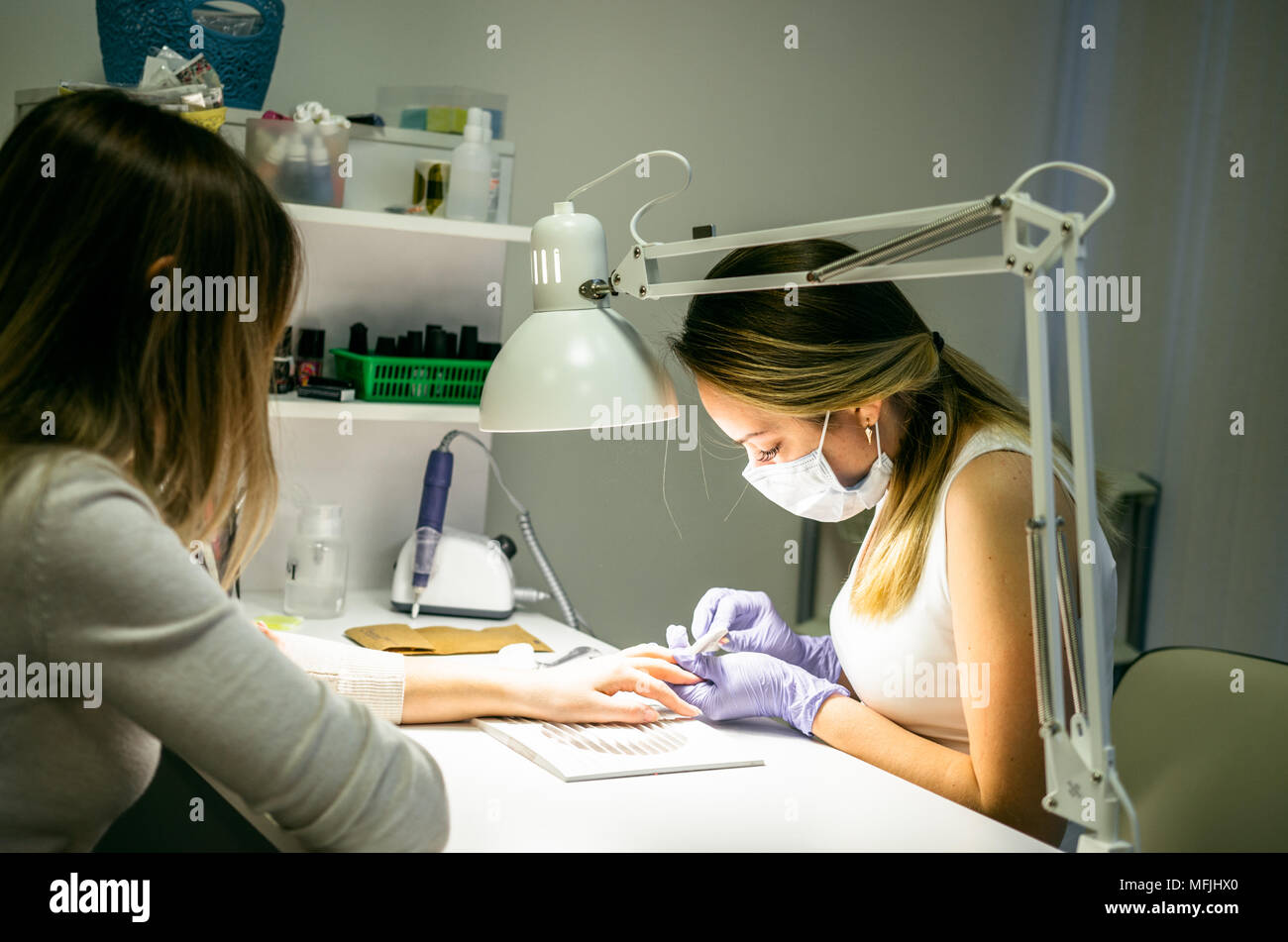 Manicurist removing cuticle nail at beauty salon Stock Photo