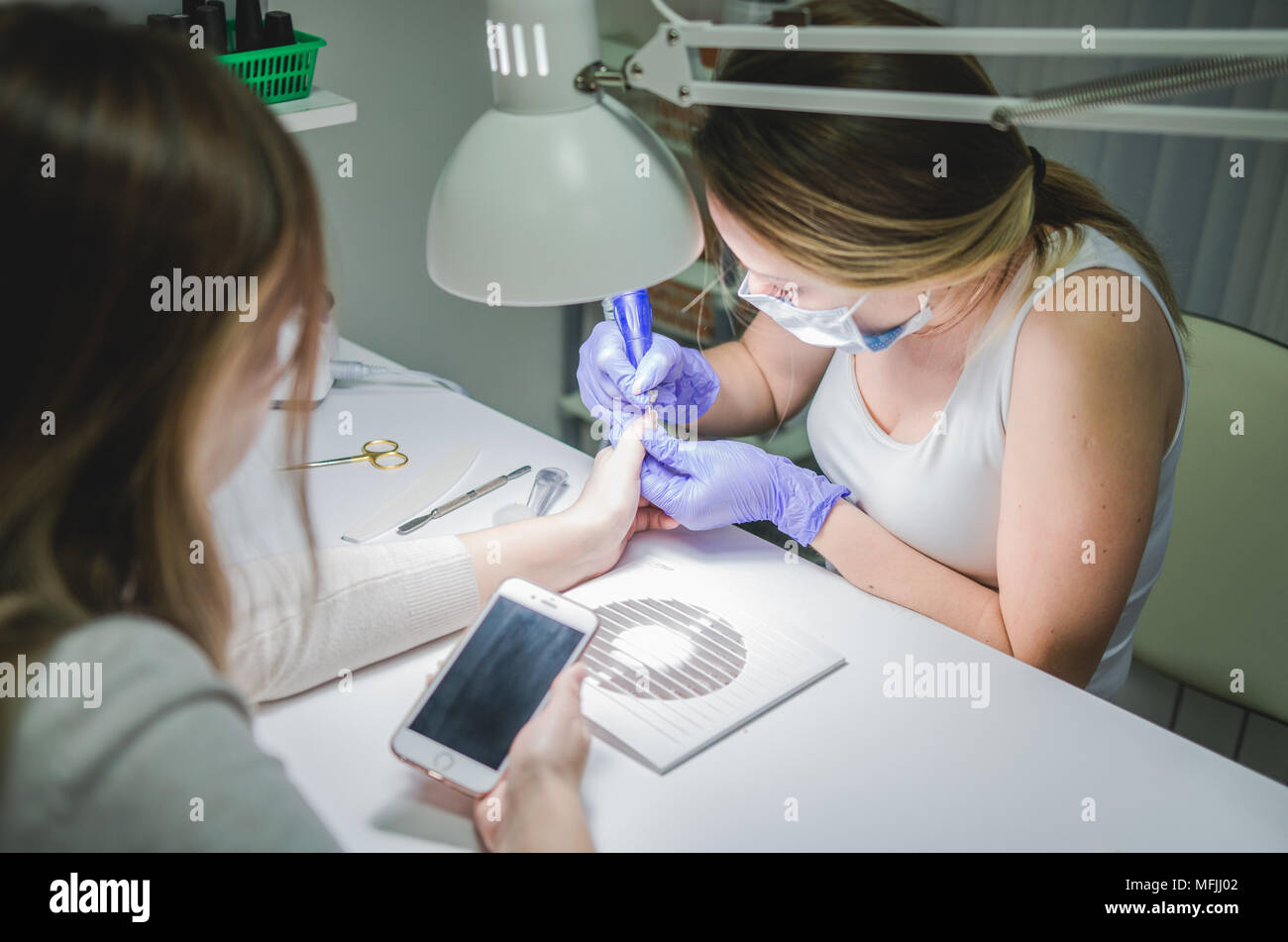 Beauty salon. Professional manicure procedure. Smartphone in hands of client Stock Photo