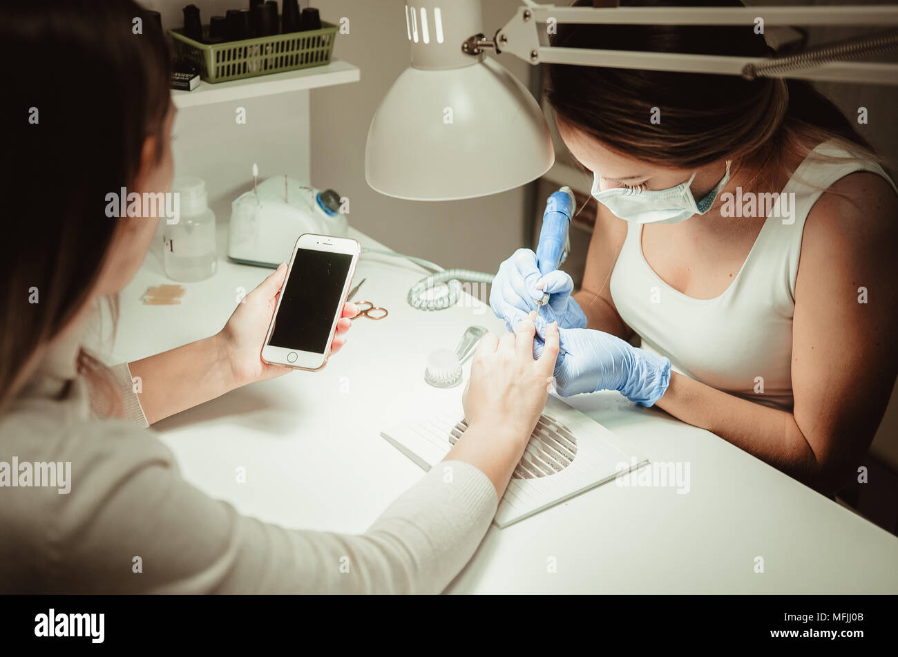 Manicure procedure. Smartphone in hands of client. Beauty salon Stock Photo