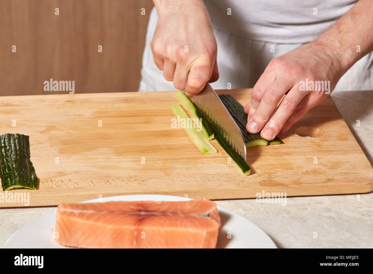 https://c8.alamy.com/comp/MFJJE5/chef-making-sushi-rolls-hands-cutting-cucumber-and-salmon-fish-MFJJE5.jpg