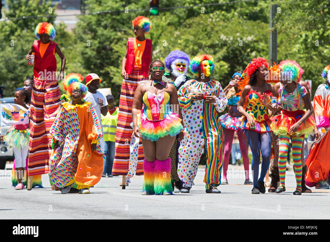 People wearing colorful clown costumes and walking on stilts