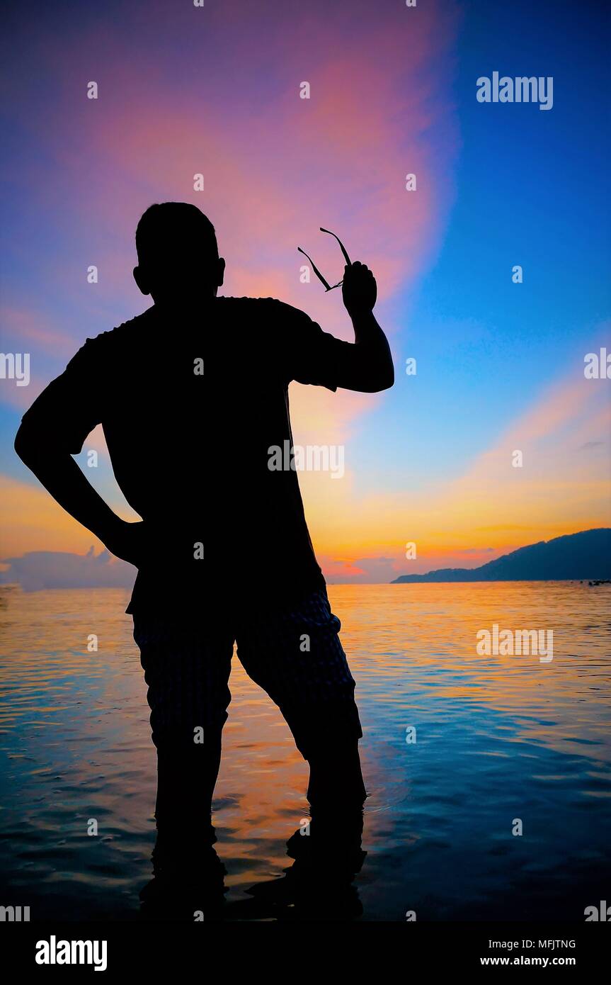 Silhouette of young man on the beach at sunset Stock Photo - Alamy