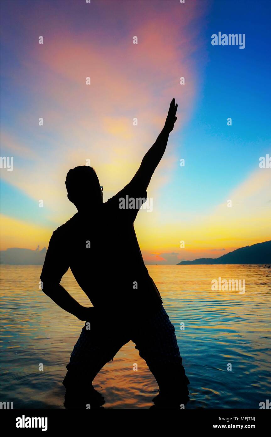Silhouette of young man on the beach at sunset Stock Photo - Alamy