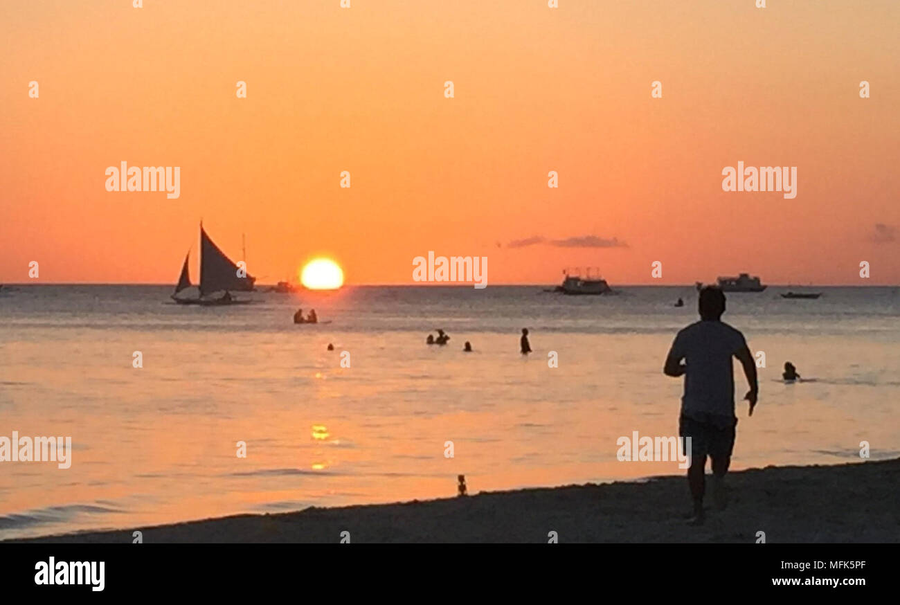 24 April 2018, Philippines, Boracay Island: Tourists strolling on the beach at sunset. A few weeks ago the island was still a dream goal. For some, the island was the most beautiful in the world. That is until the president of the Philippines called it a cesspit. At least the island is fully booked for the next six months. Photo: Girlie Linao/dpa Stock Photo