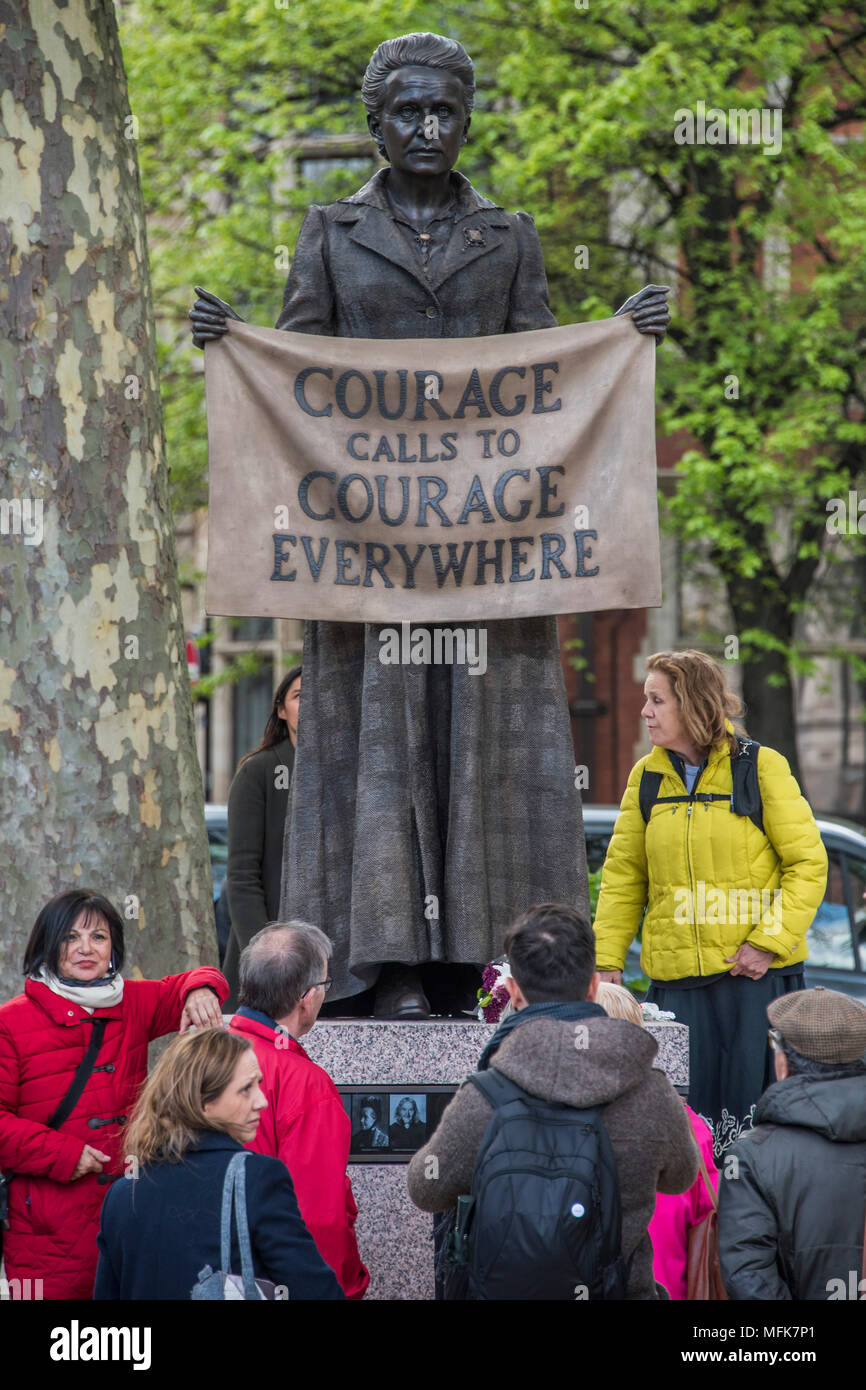 London, UK. 26th Apr, 2018. Tourists examine the new statue - 8ft 4in bronze statue of the suffragist campaigner Millicent Fawcett is now in the shadow of the Houses of Parliament following a campaign led by Criado-Perez. It was created by Turner prize-winning artist Gillian Wearing, and shows Fawcett when she became president of the National Union of Women’s Suffrage Societies. She holds a banner that reads: “Courage Calls to Courage Everywhere”, an extract from a speech Fawcett made after the death of suffragette Emily Wilding Davison. Credit: Guy Bell/Alamy Live News Stock Photo