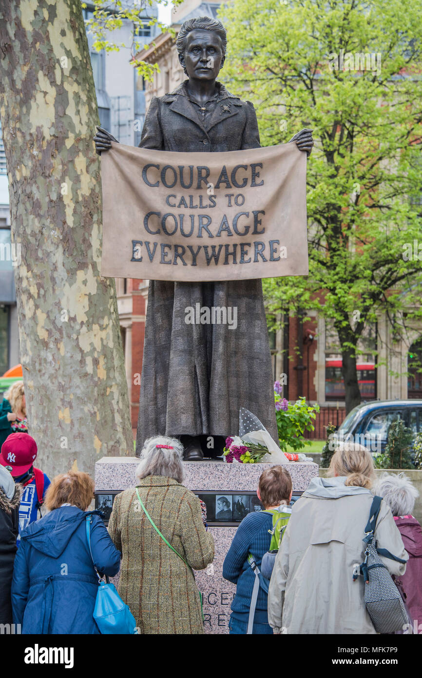 London, UK. 26th Apr, 2018. Tourists examine the new statue - 8ft 4in bronze statue of the suffragist campaigner Millicent Fawcett is now in the shadow of the Houses of Parliament following a campaign led by Criado-Perez. It was created by Turner prize-winning artist Gillian Wearing, and shows Fawcett when she became president of the National Union of Women’s Suffrage Societies. She holds a banner that reads: “Courage Calls to Courage Everywhere”, an extract from a speech Fawcett made after the death of suffragette Emily Wilding Davison. Credit: Guy Bell/Alamy Live News Stock Photo