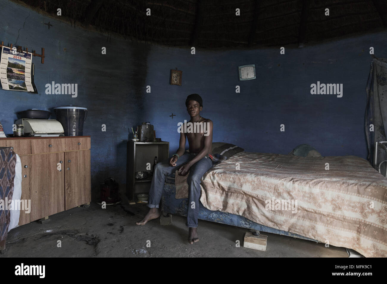 January 12, 2018 - Matatiele, Eastern Cape, South Africa - Luis, 14, sits on the bed in one of his family's mud houses, which he shares with his older brother and father. The blue round shaped house serves as a sleeping room, community area and as a kitchen. (Credit Image: © Stefan Kleinowitz via ZUMA Wire) Stock Photo