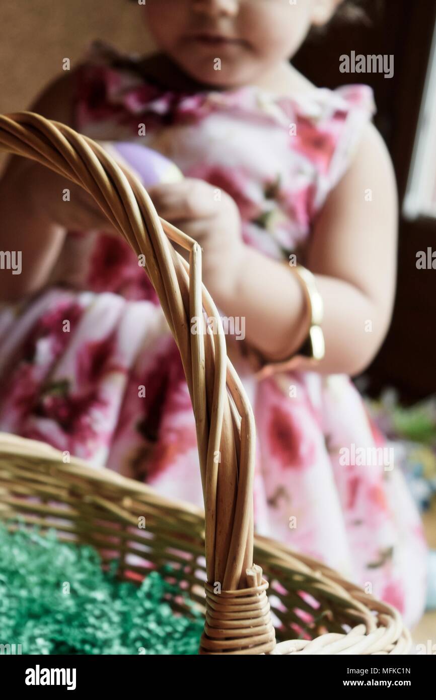 An hispanic girl in a floral dress opens her Easter basket Stock Photo