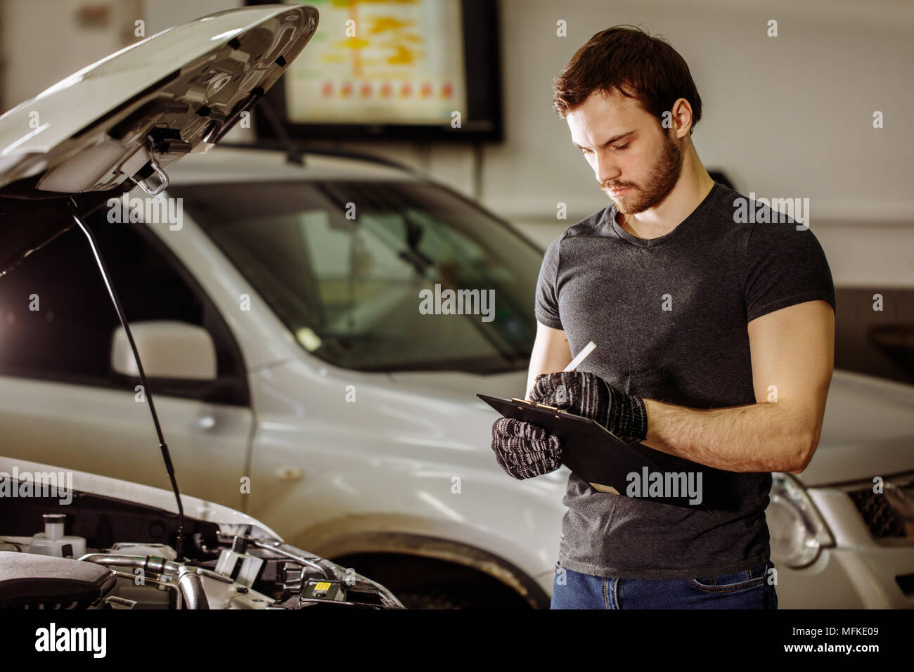 Automechanic controlling car with checklist in repair garage Stock ...