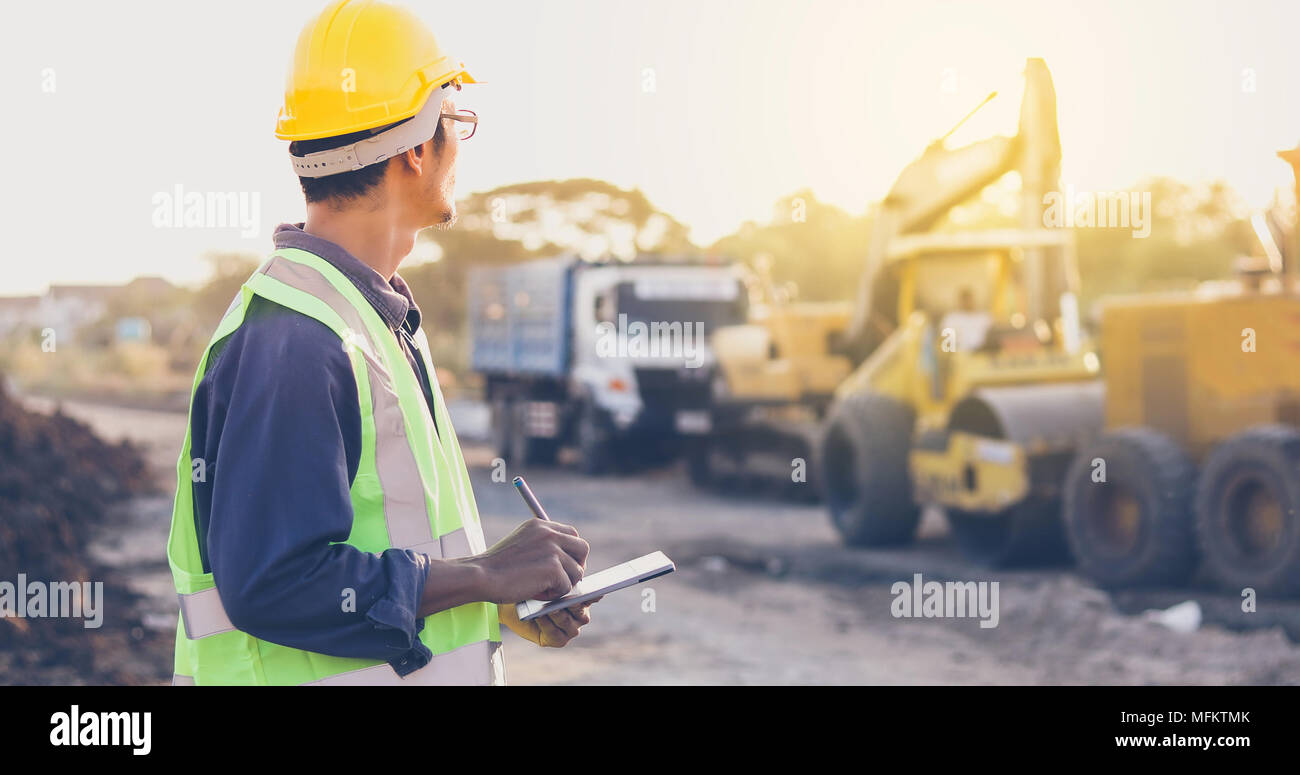 Asian engineer with hardhat using  tablet pc computer inspecting and working at construction site Stock Photo