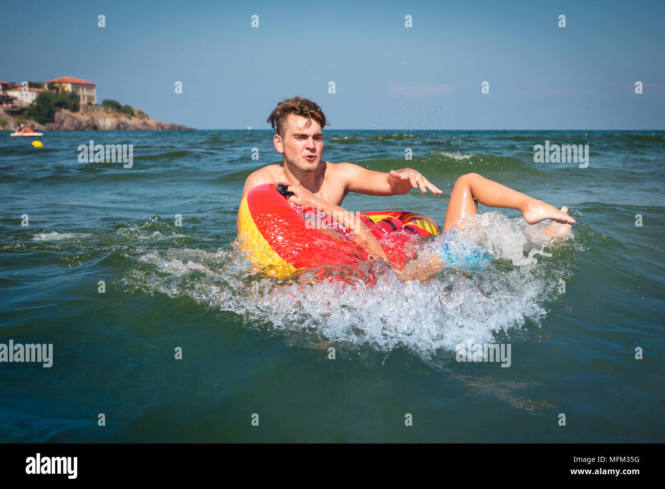Young father playing with a child in the sea and makes mistake and let out child into waves. Little boy falls from inflatable mattress in water. Stock Photo