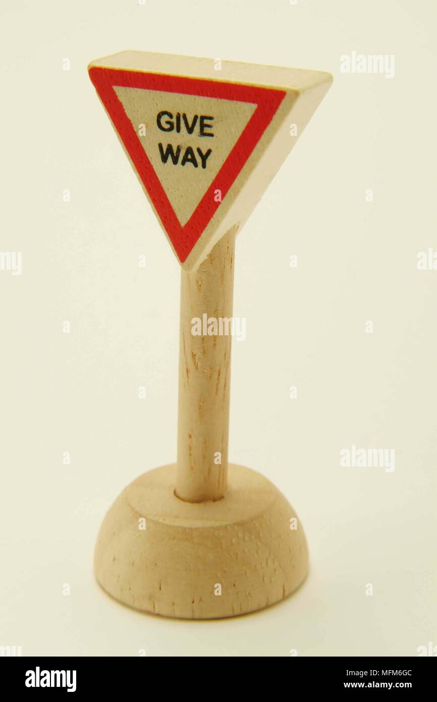 A side view of a simple wooden toy road sign directing traffic to give