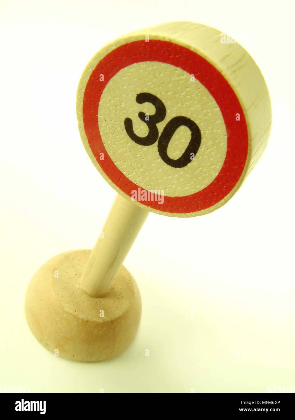 A high dramatic side view of a simple wooden toy road sign showing a 30 ...