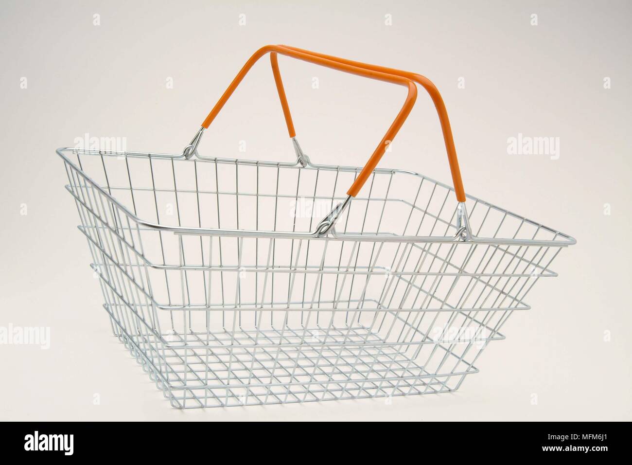 An empty instore hand held wire shopping basket on a plain white