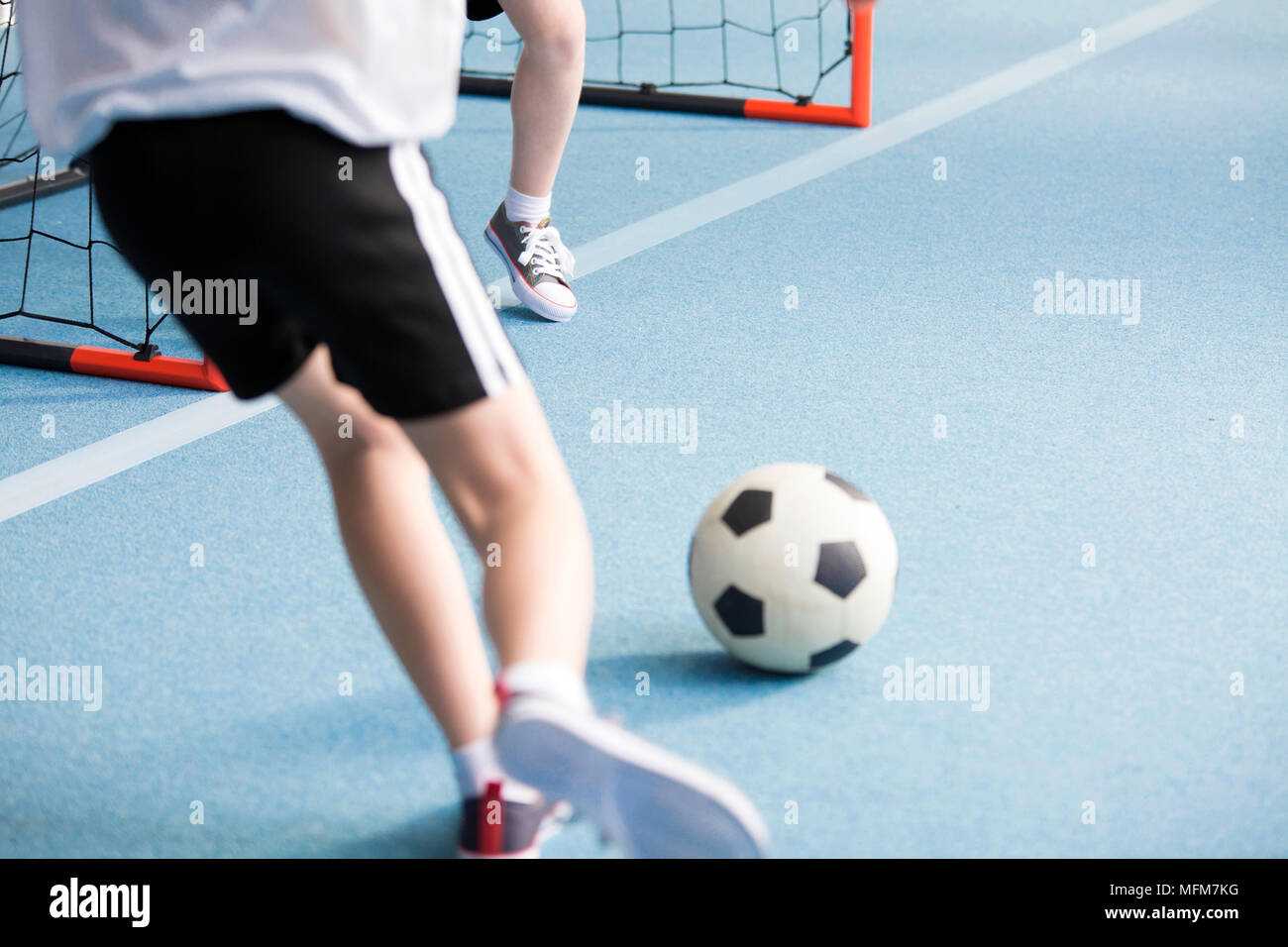 Close-up of a boy playing soccer with his friend at the sports hall Stock Photo