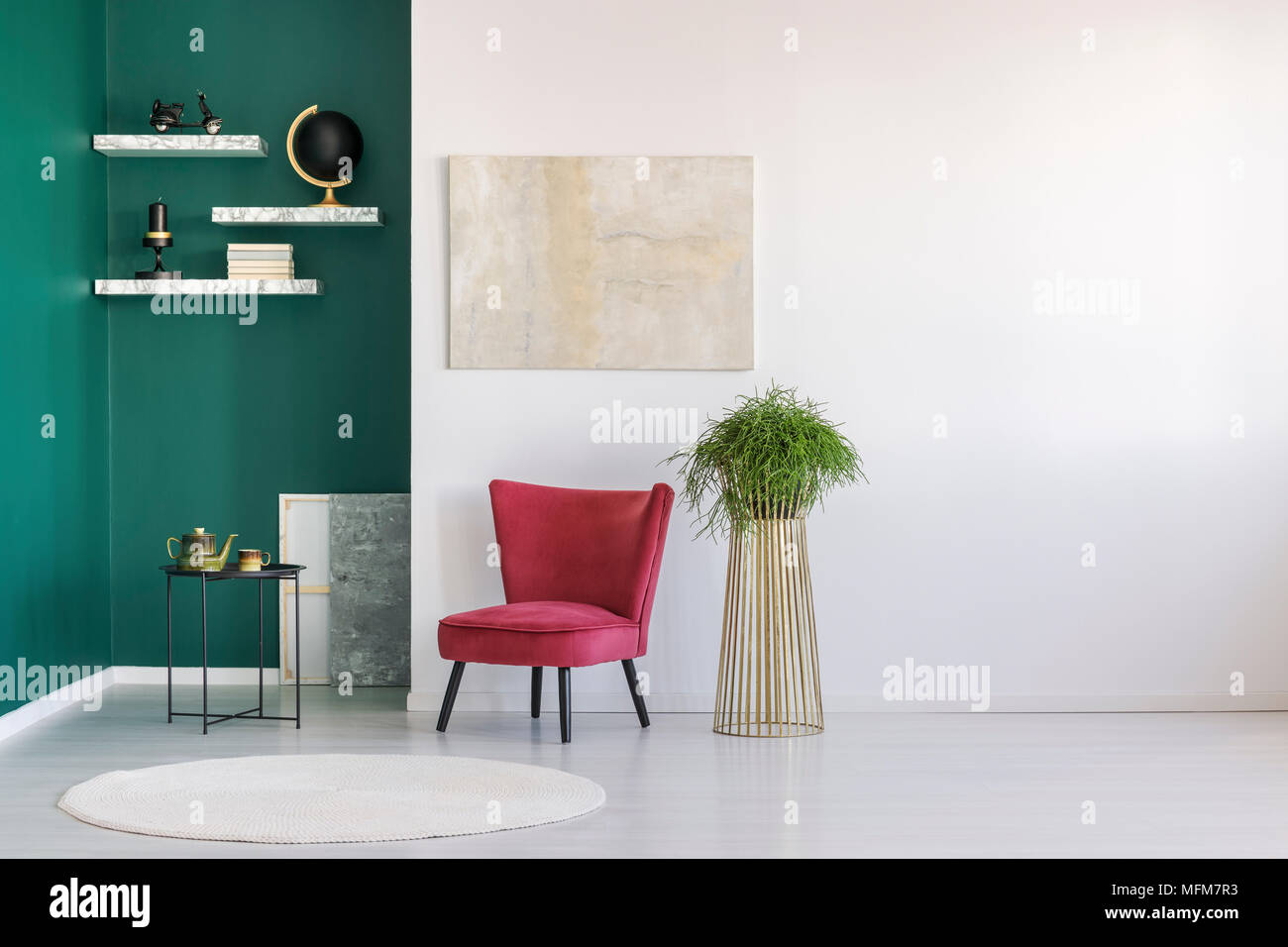 Comfortable retro, red chair and a gold, metal plant stand in a