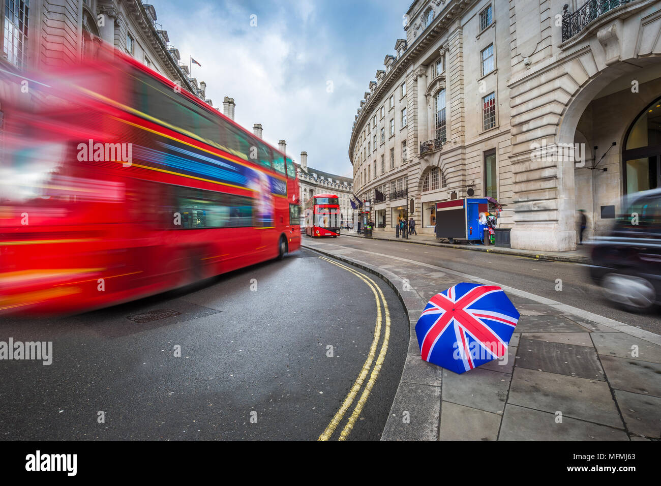 London, England - Iconic red double-decker buses and black taxi on the move on Regent Street with british umbrella Stock Photo