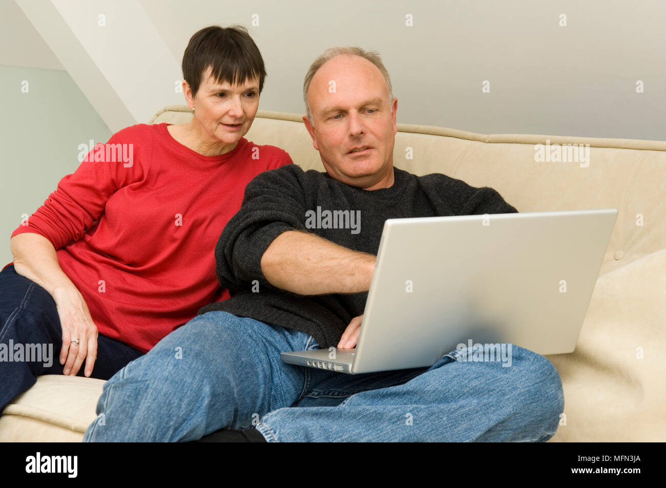 Mature couple sitting on a couch and using a laptop Ref: CRB410 10003 ...