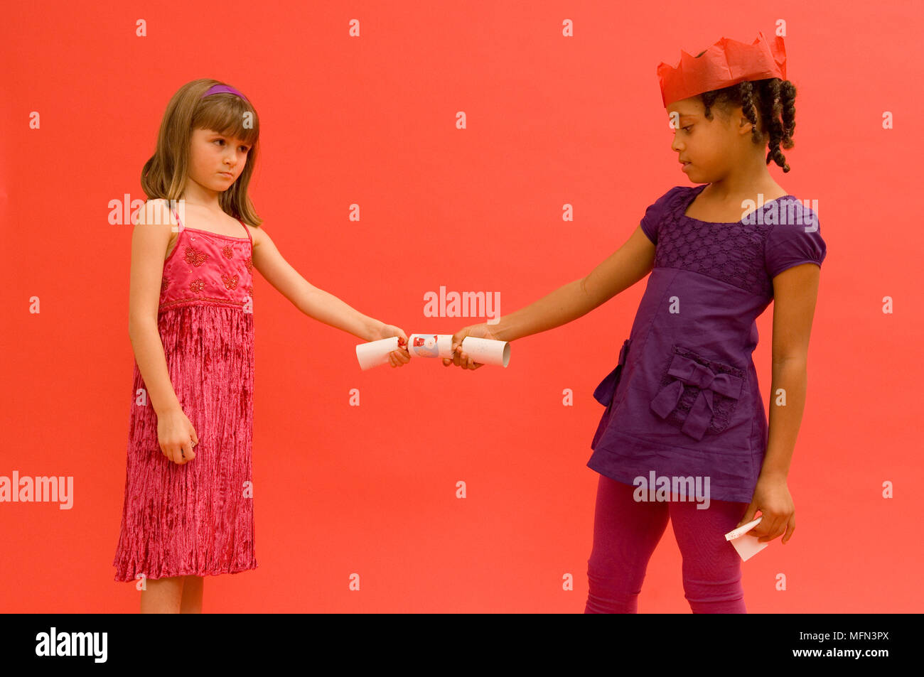 Close-up of two girls pulling a christmas cracker   Ref:   Compulsory Credit: Stock Photo