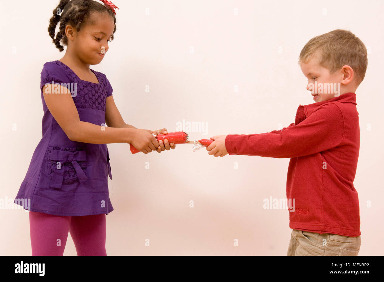 Side profile of a boy and a girl pulling a christmas cracker   Ref:   Compulsory Credit: Stock Photo