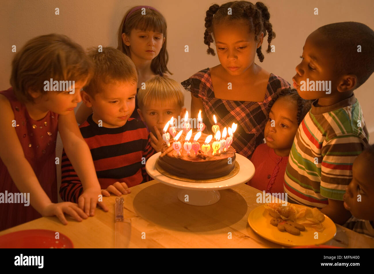 group-of-children-standing-in-front-of-a-birthday-cake-at-a-birthday