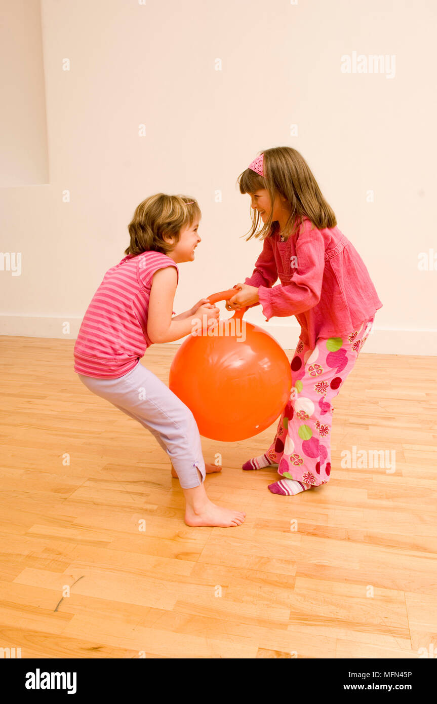 Side profile of two girls pulling a space hopper   Ref:   Compulsory Credit: Stock Photo