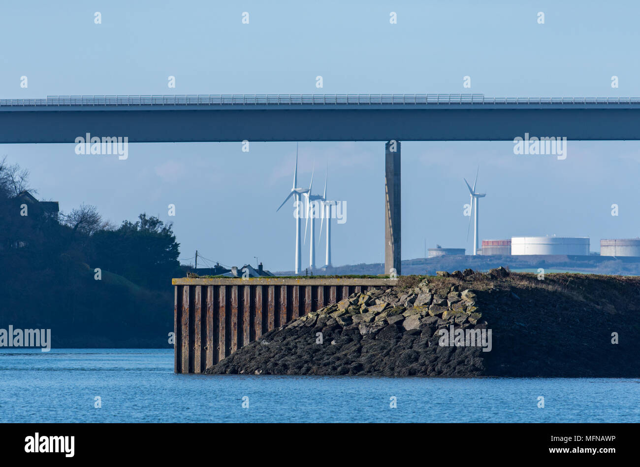 Wind turbines and oil storage tanks behind he NATO jetty and Cleddau bridge, Milford Haven Stock Photo