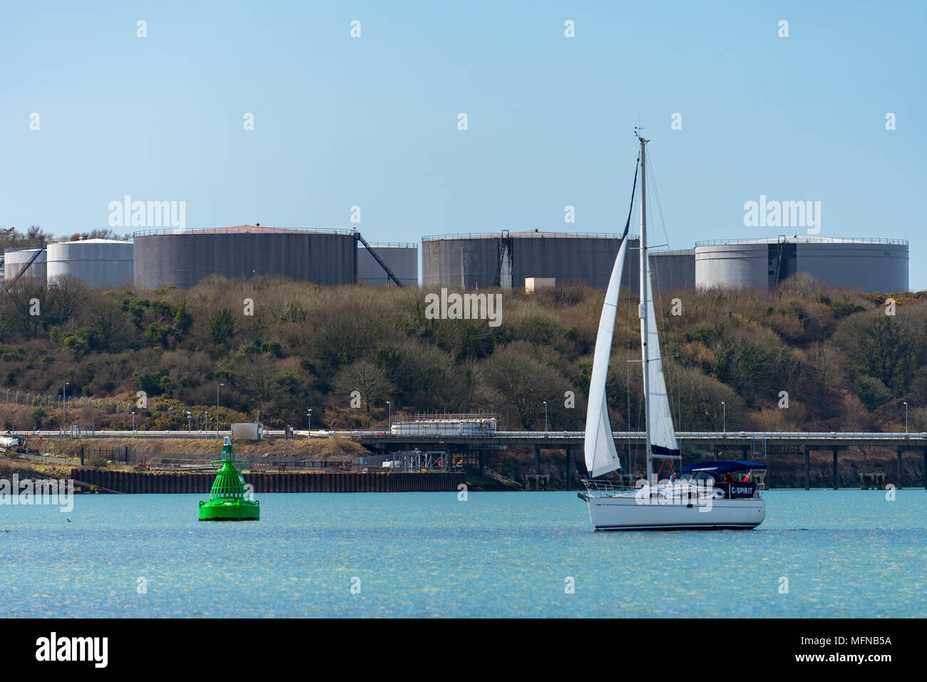 Yacht sailing with petrochemical industry behind Stock Photo