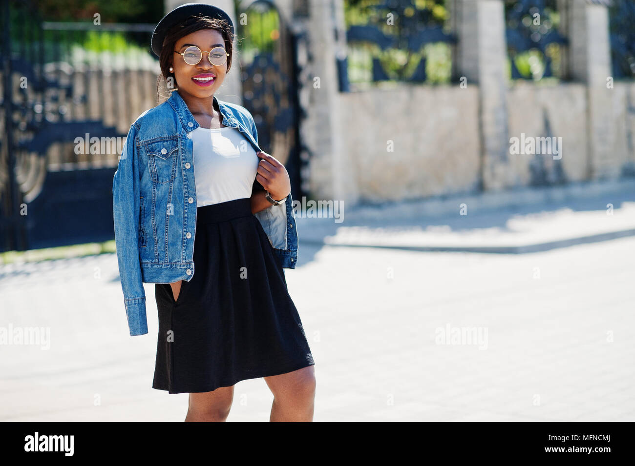 Stylish african american model in glasses hat, jeans jacket and black skirt  posed outdoor Stock Photo - Alamy