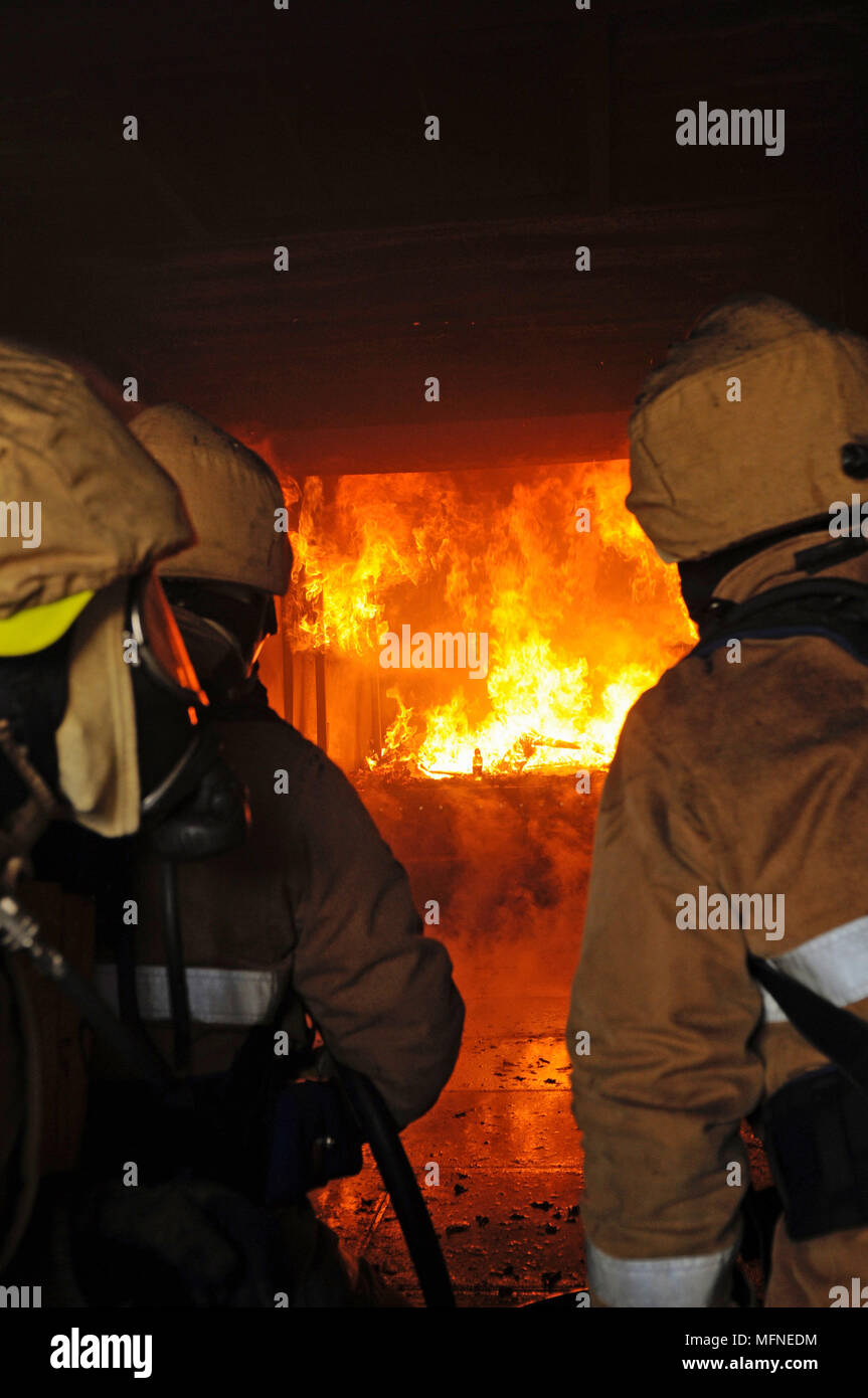 Fireman on a fire training ground donning breathing apparatus for an exercise Stock Photo