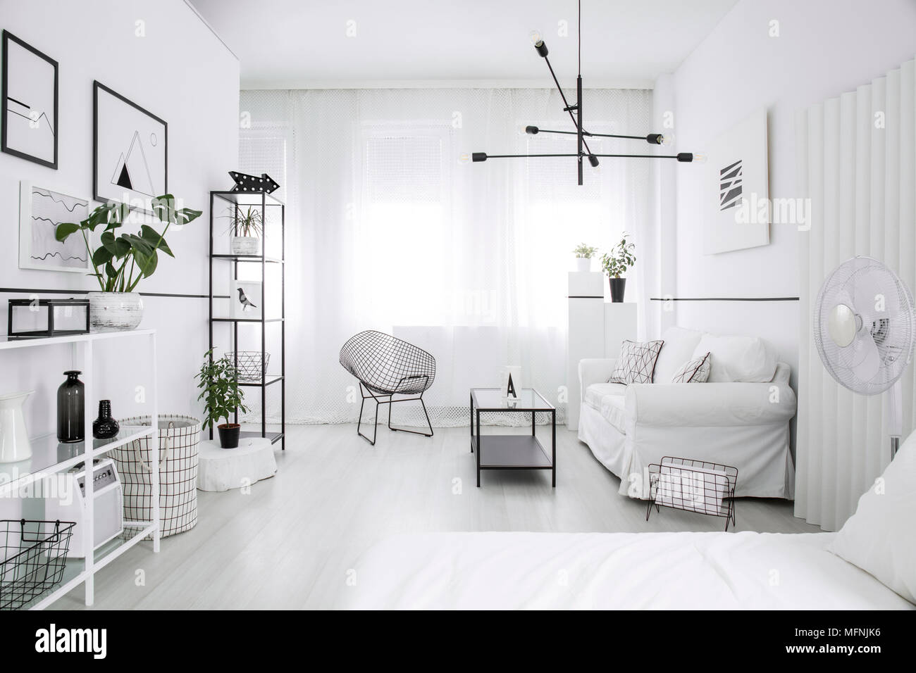 Spacious, furnished bedroom interior with a bed, couch, table, shelves