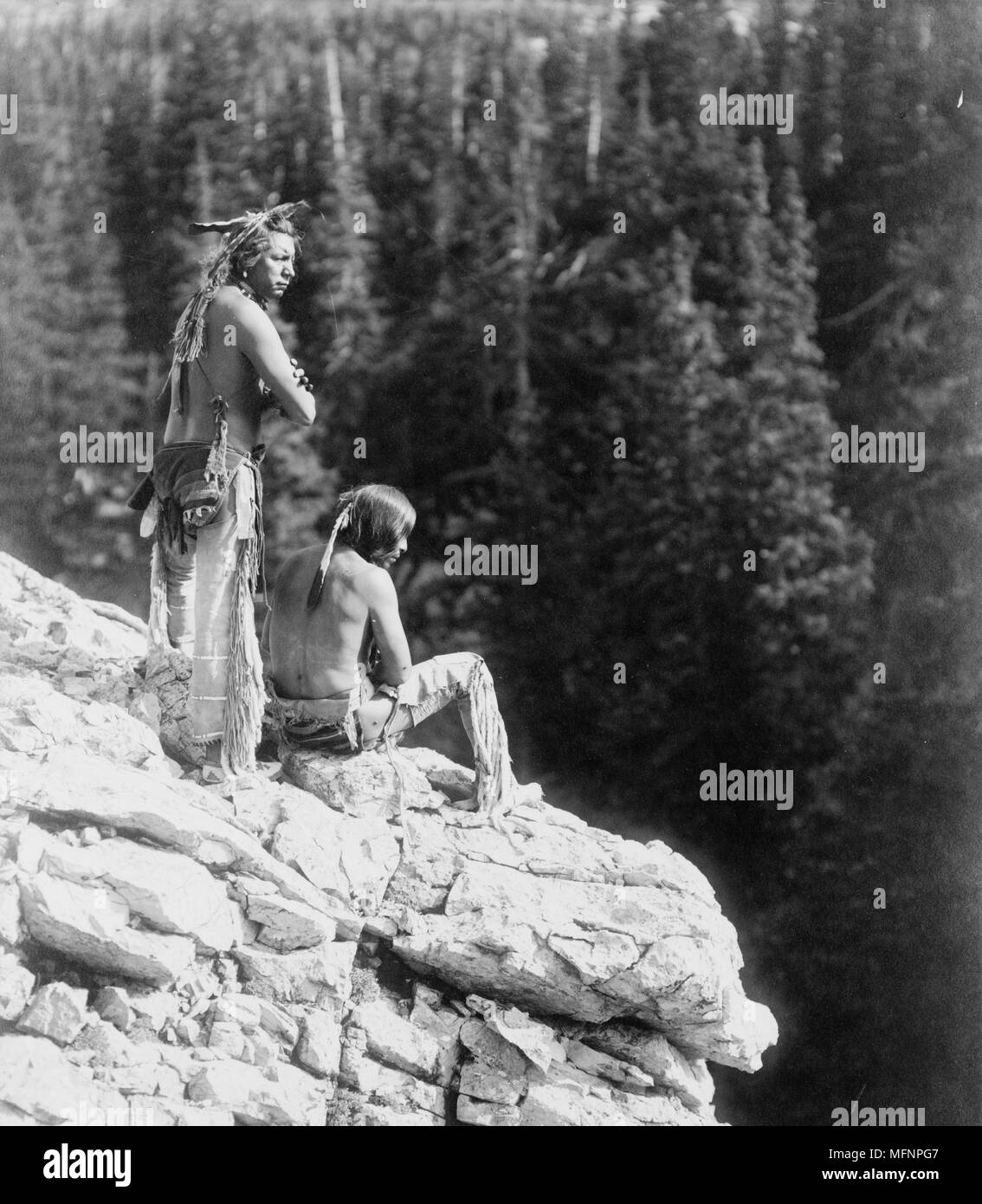 Two Native Americans looking over the edge of a cliff, c1912.  Photograph by Roland W. Reed (1864-1934). Stock Photo